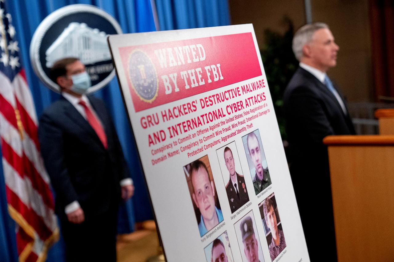 Photo: A poster showing six wanted Russian military intelligence officers is displayed as U.S. Attorney for the Western District of Pennsylvania Scott Brady, accompanied by Assistant Attorney General for the National Security Division John Demers, speaks at a news conference at the Department of Justice, in Washington, U.S., October 19, 2020. Credit: Andrew Harnik/Pool via REUTERS