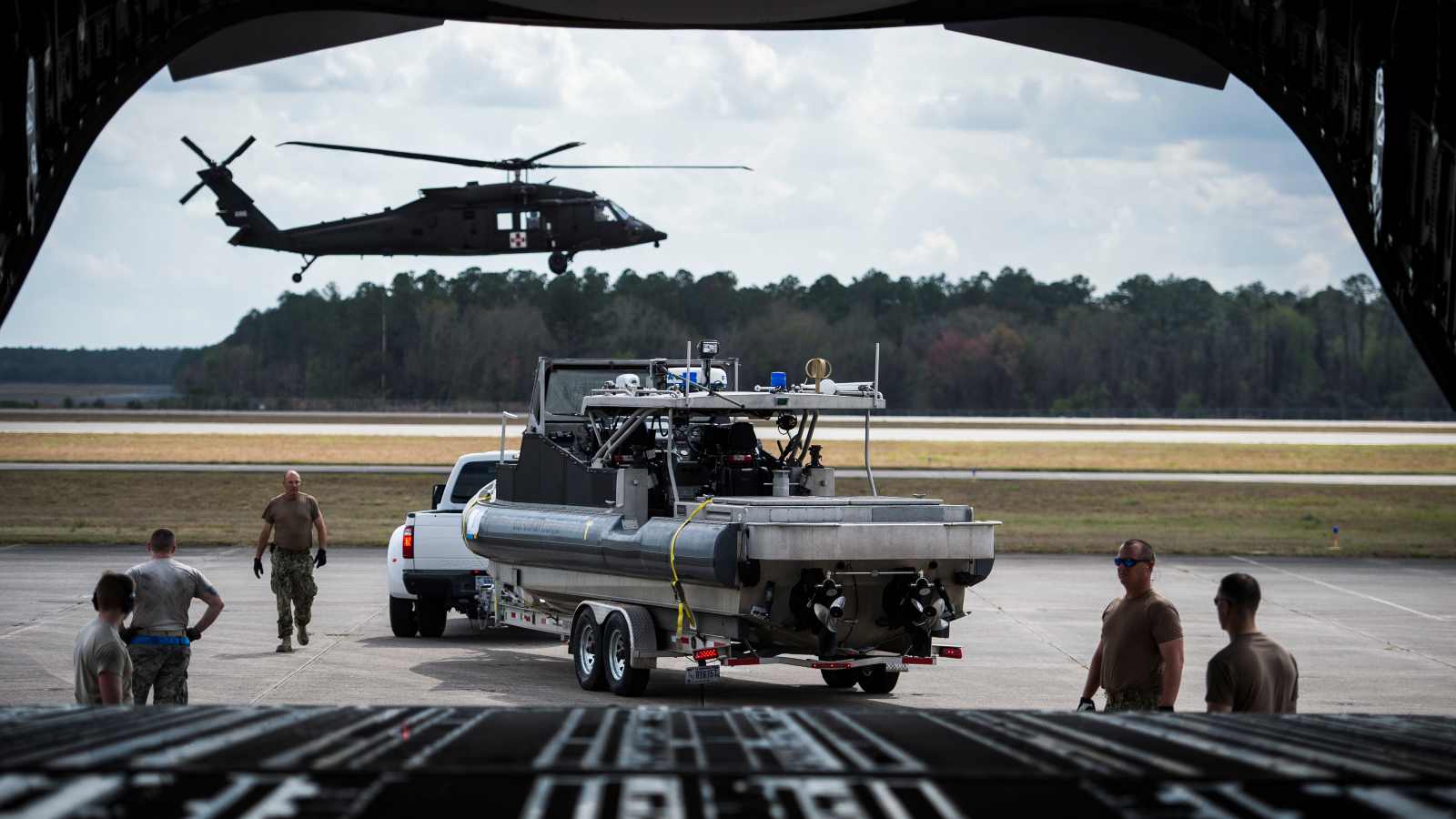 A U.S. Coast Guard boat is parked in position to be loaded onto an Air Force C-17 Globemaster, as an Army UH-60 Black Hawk prepares to land during Exercise Patriot Sands, Naval Air Station Cecil Field, Florida, Feb. 22, 2019. Exercise Patriot Sands is a joint-service exercise coordinated by the Air Force Reserve, designed to integrate first responders from federal, state, local agencies and the military by providing quick response training in the event of a regional emergency or natural disaster. (U.S. Air Force photo by Tech. Sgt. Larry E. Reid Jr.)