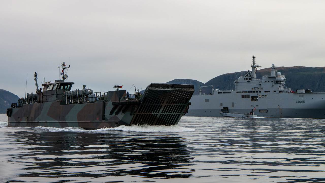 A Dutch Landing Craft LCVP passes by FS Dixmude A in K-Town Fjords while performing an Amphibious Assault as part of Livex of Trident Juncture 18.