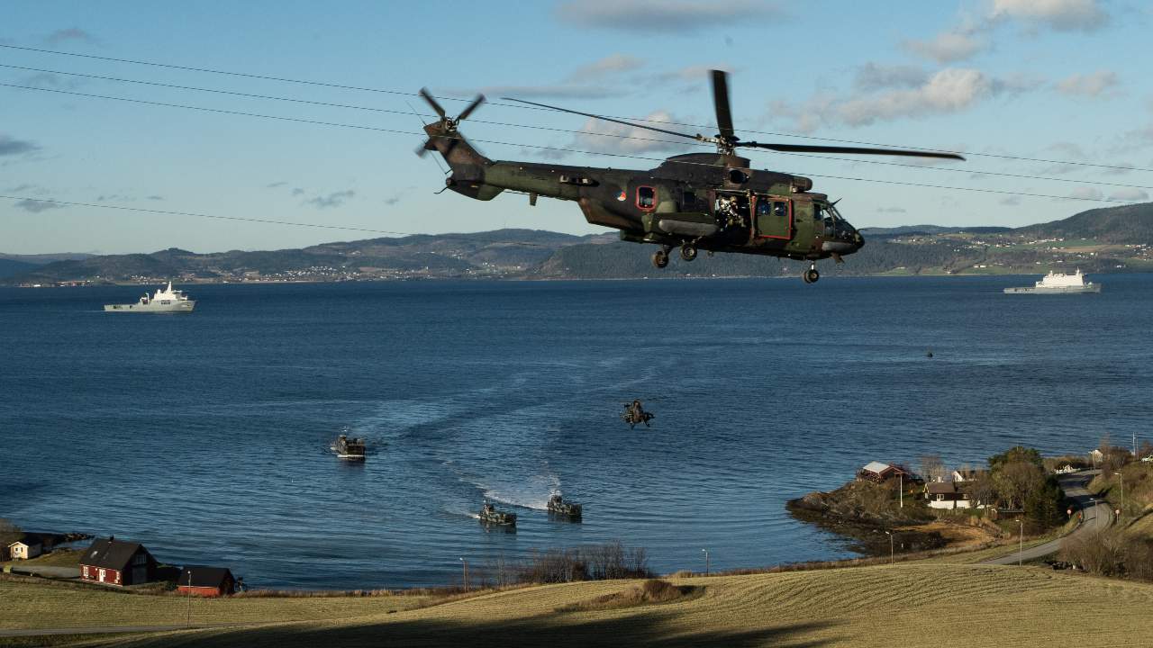 A Dutch AS532 Super Puma helicopter securises the landing of infantrymen on the beach of Trondheim Fjord, in Norway, during exercise Trident Juncture 18.