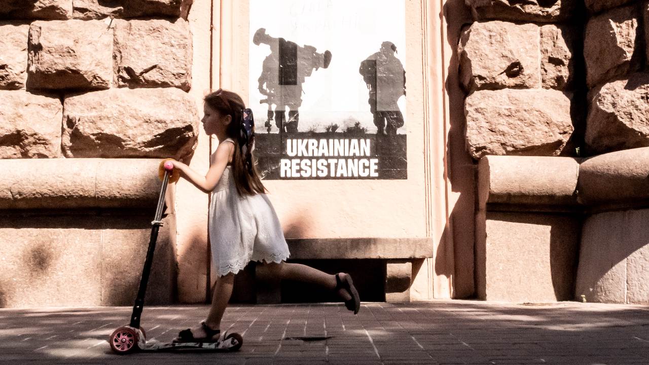 Photo: A girl passes by a poster with a sign "Ukrainian resistance' in an Old Town of Kyiv, Ukraine on June 8, 2022. As the Russian Federation invaded Ukraine 3 and a half months ago, fierce fighting continues in the East of the country. The capital, Kyiv stays in relative safety, though reminders of the war such as protective sand bags, road blocks, national and anti-war symbols are present all over the city. Credit: Dominika Zarzycka/NurPhoto
