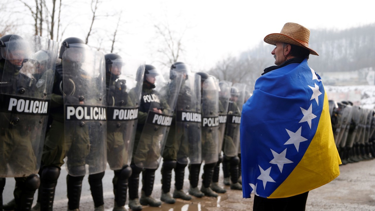 Photo: A former army member wrapped in flag of Bosnia and Herzegovina stands in front of members of SPJ ZDK (Special Police Forces) during an attempt to block the main road at a protest in Doboj, Bosnia and Herzegovina March 3, 2018. Credit: REUTERS/Dado Ruvic