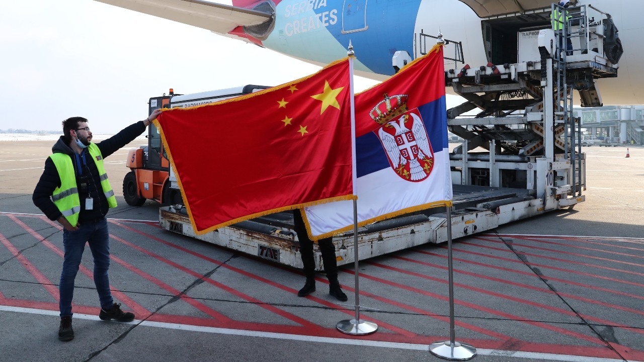 A man holds China's flag next to Serbia's flag as a plane transporting one million doses of Sinopharm's China National Biotec Group (CNBG) vaccines for the coronavirus disease (COVID-19) arrives at Nikola Tesla Airport in Belgrade, Serbia, January 16, 2021. REUTERS/Marko Djurica