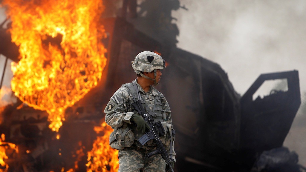 Photo: Captain Melvin Cabebe with the US Army's 1-320 Field Artillery Regiment, 101st Airborne Division stands near a burning M-ATV armored vehicle after it struck an improvised explosive device (IED) near Combat Outpost Nolen in the Arghandab Valley north of Kandahar, Afghanistan, July 23, 2010. Credit: REUTERS/Bob Strong/File Photo.