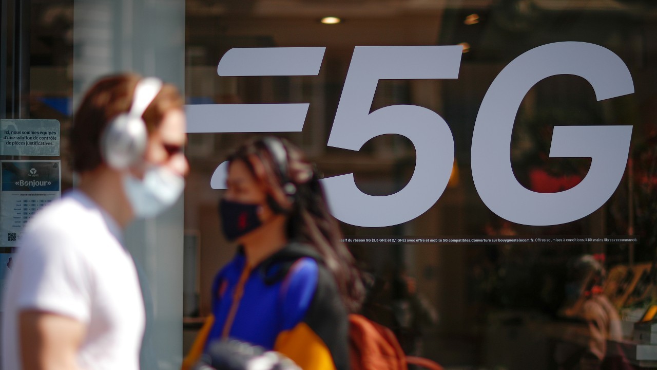 Photo: People, wearing protective face masks, walk past a 5G data network sign at a mobile phone store in Paris, France, April 22, 2021. Credit: REUTERS/Gonzalo Fuentes