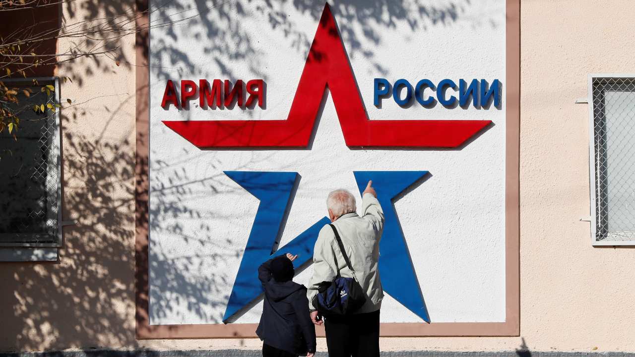 Photo: Local residents look at a banner on the Operational Group of Russian Forces headquarters in Tiraspol, in Moldova's self-proclaimed separatist Transdniestria, November 3, 2021. The banner reads "Army of Russia". Credit: REUTERS/Gleb Garanich