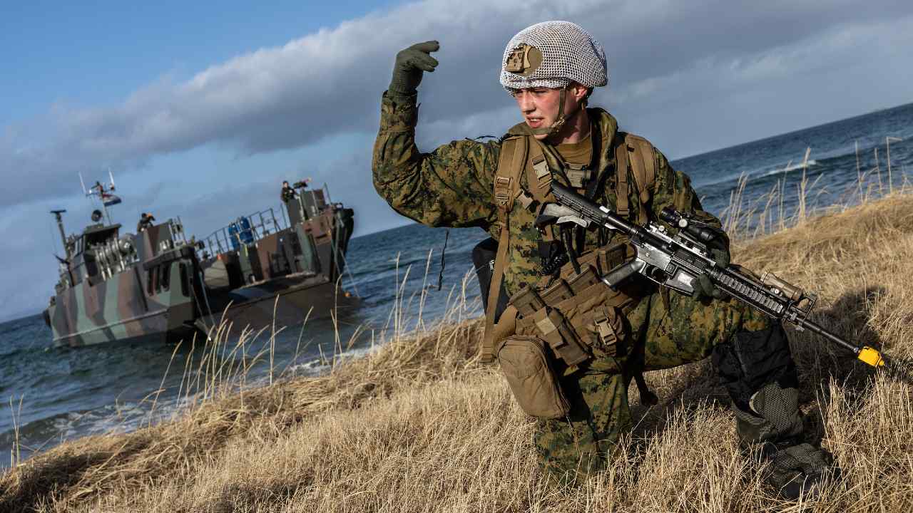 Photo: A US marine waves his troops onward after using Dutch landing craft to land near Sandstrand, Norway on 21 March during Exercise Cold Response 22. Dutch, French, and US forces have landed in Norway for the long-planned Exercise Cold Response 22. Credit: NATO via Flickr.