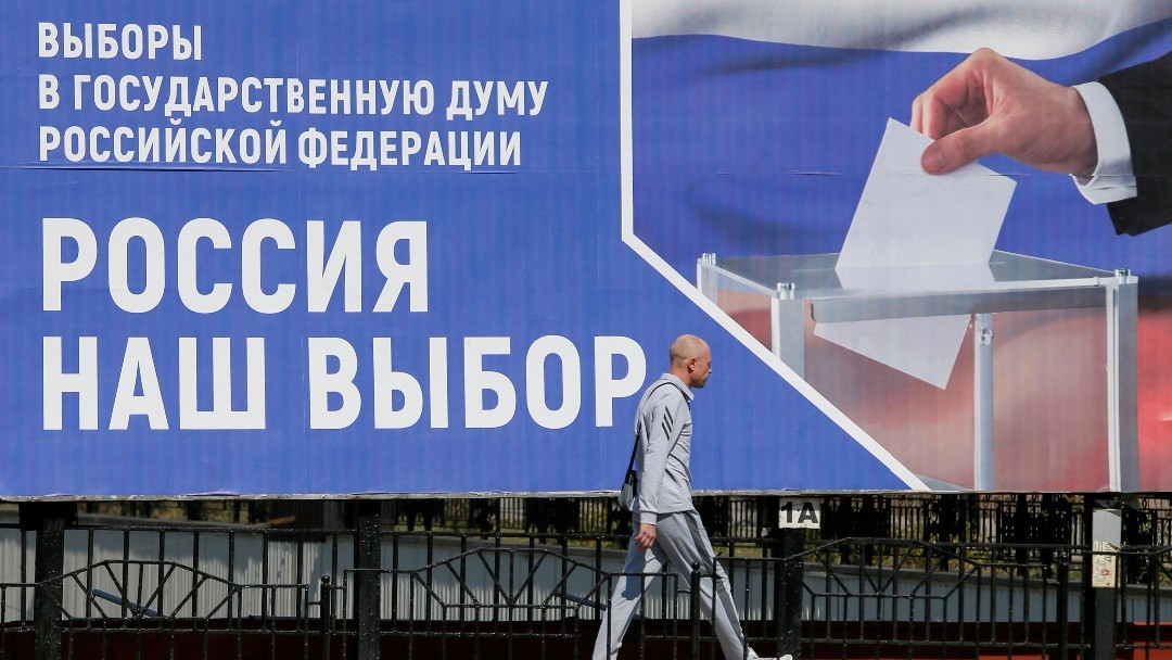 Image: pedestrian walks past a board informing of the upcoming Russian parliamentary elections in a street in the rebel-held city of Donetsk, Ukraine September 9, 2021. A board promotes to take part in the election by voting at polling stations in Russia's Rostov Region and reads: "Russia is our choice". Credit: REUTERS/Alexander Ermochenko/File Photo.