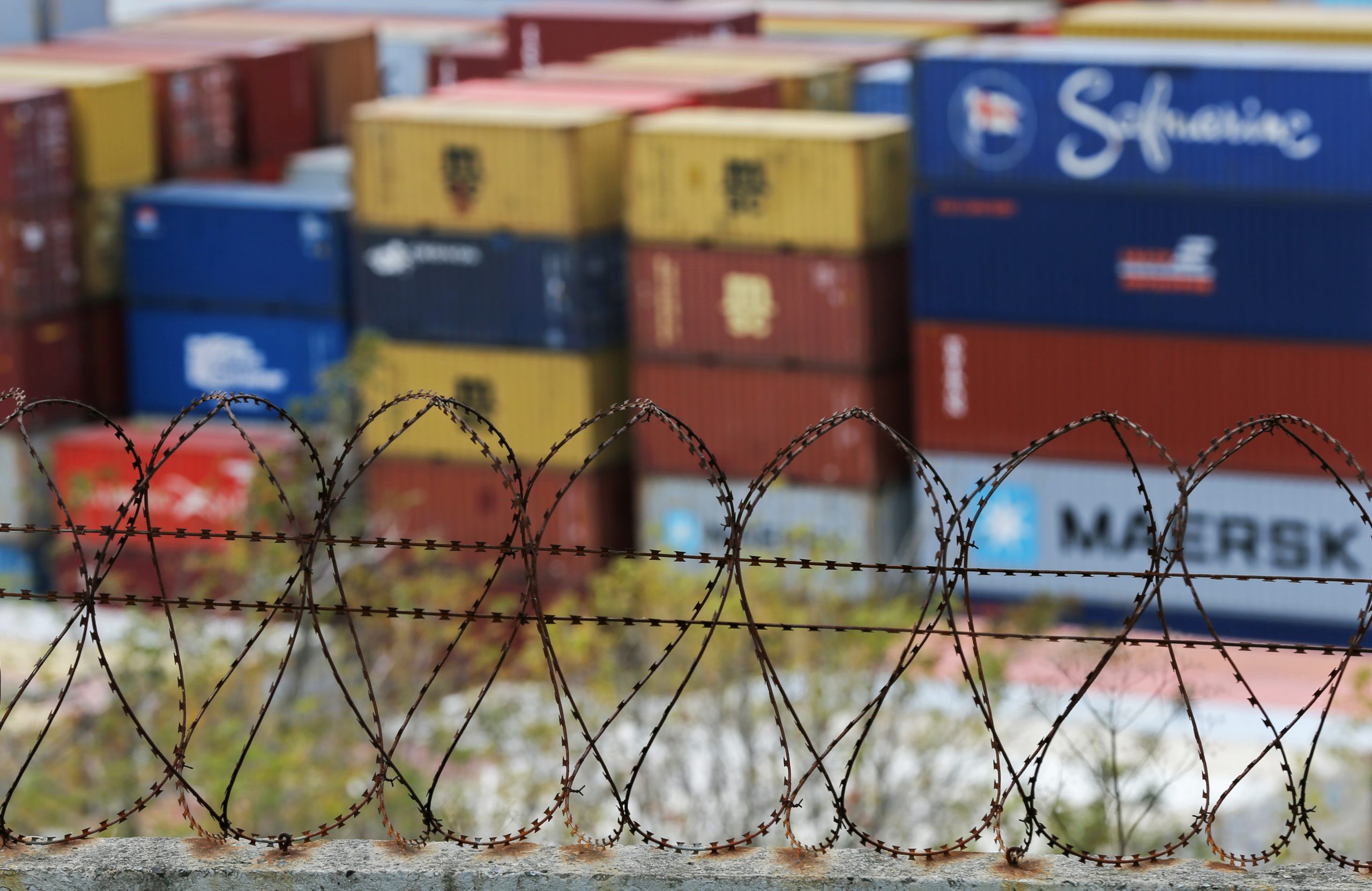 Photo: Stacked shipping containers are seen behind barbed wire at a commercial port in Vladivostok, Russia October 18, 2021. Picture taken October 18, 2021. Credit: REUTERS/Tatiana Meel